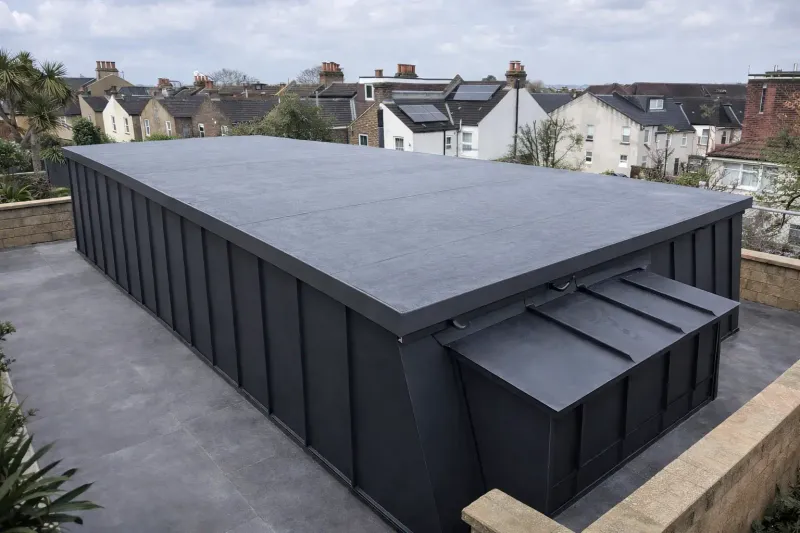 Single-ply flat roof beside dark standing seam wall cladding on a rooftop extension