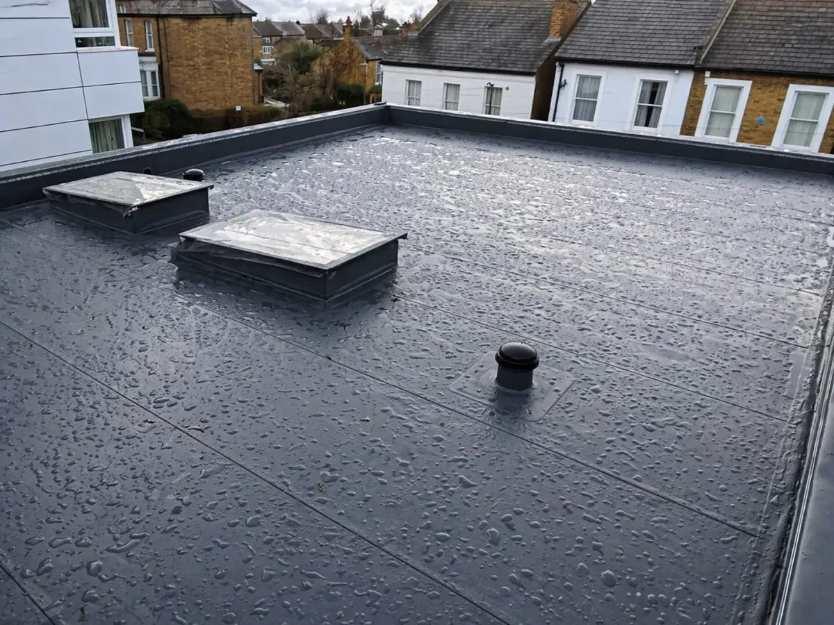 Single-ply flat roof with rooflights and rainwater outlet after rainfall