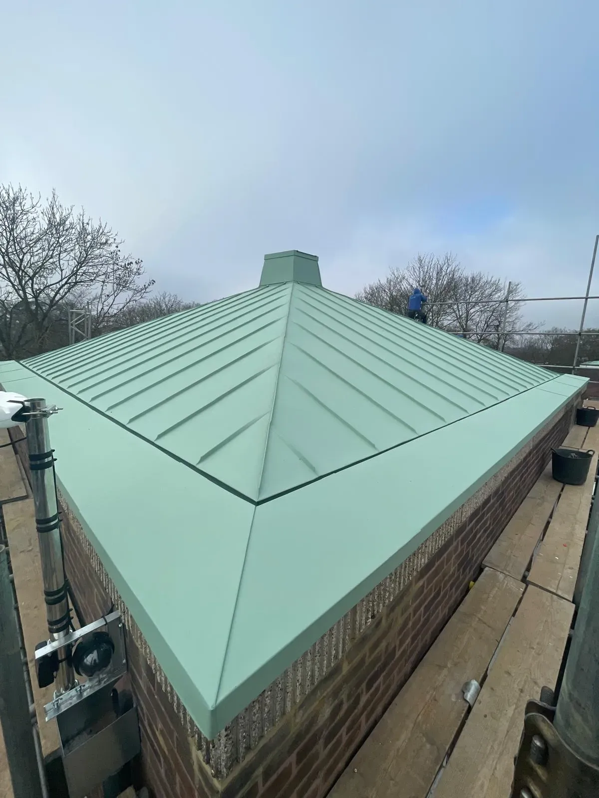 Green steel standing seam roof on a square pyramidal roof form