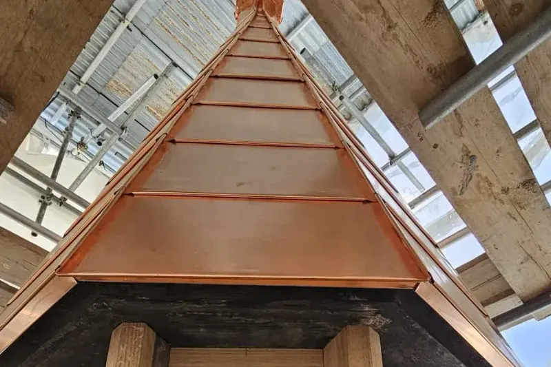 Copper-clad roof turret with natural patina above a slate roof